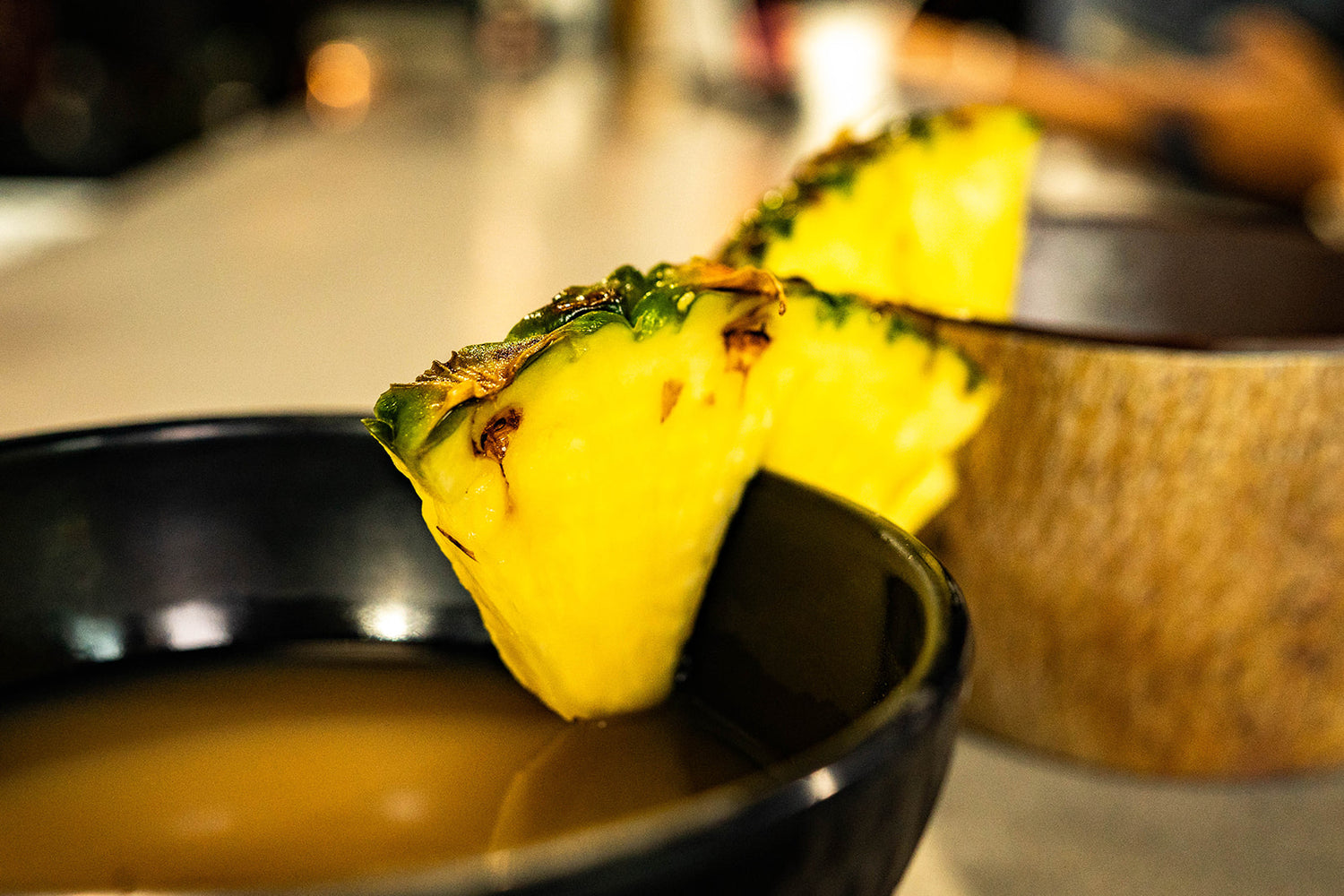 Kava bar in Miami offering kava shells with slices of fresh pineapple, inviting customers to enjoy a kava experience in a local setting in Miami.